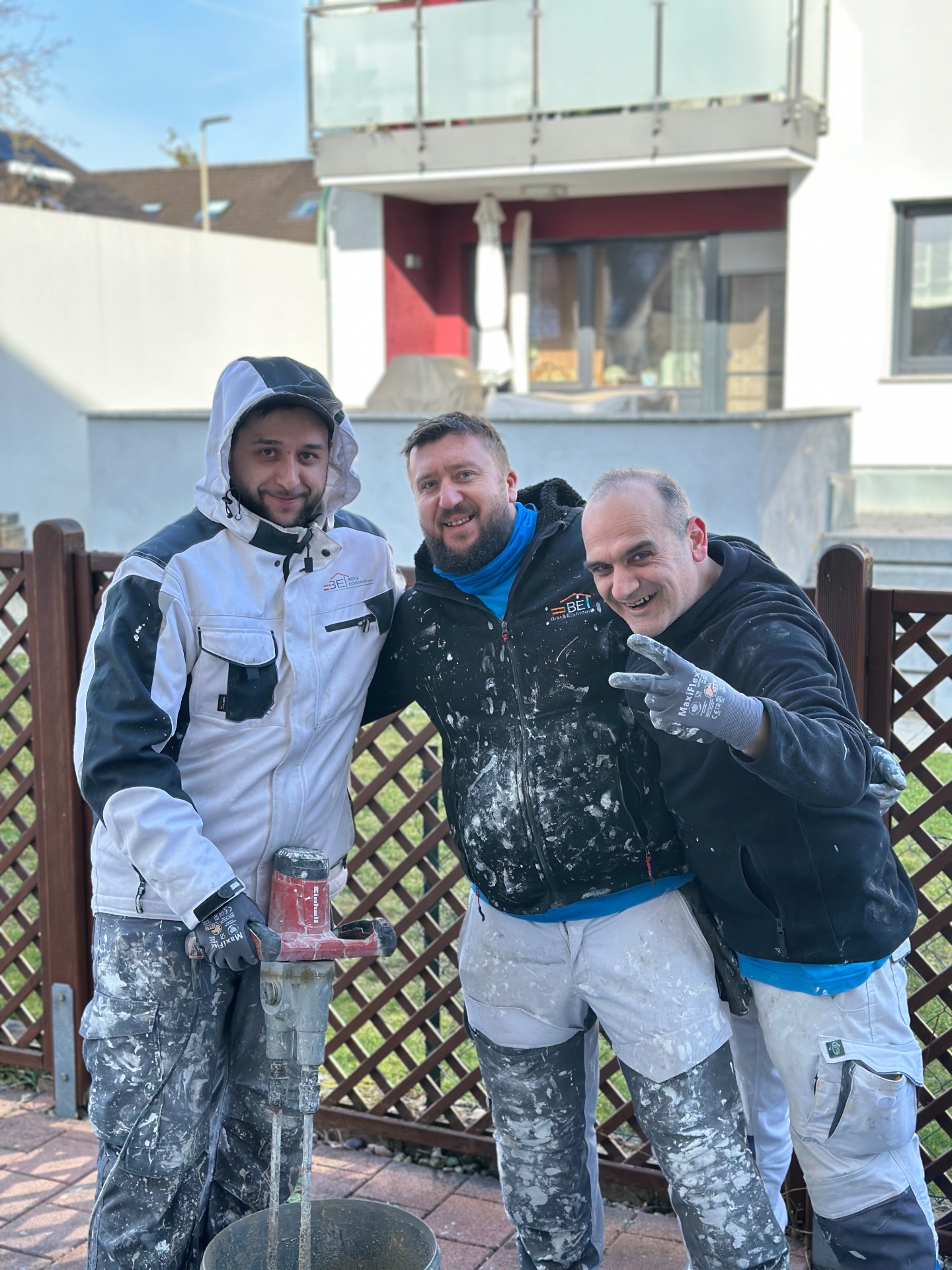 Drei Mitarbeiter der Bier & Eichmann GmbH lachen gemeinsam auf der Baustelle
